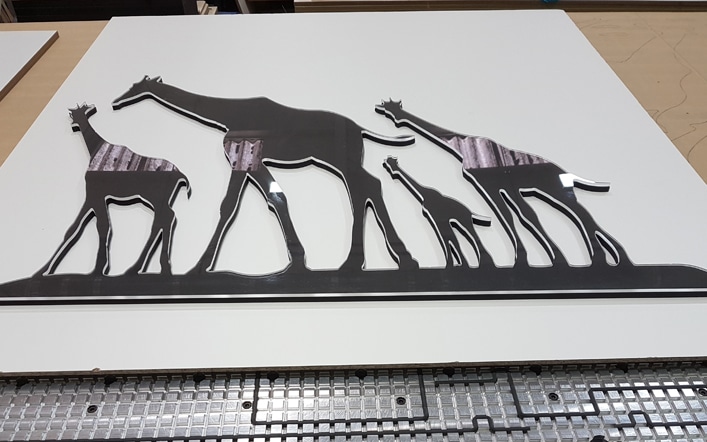 A 2D CNC cut clear acrylic over black MDF piece of wall art showing four Giraffes