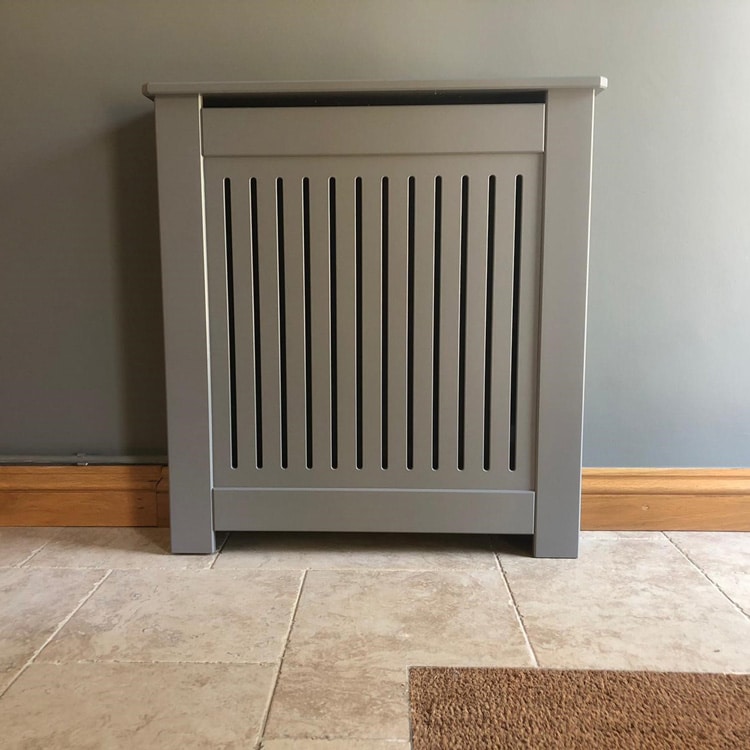 A bespoke grey painted MDF radiator cover in situ on a tiled floor