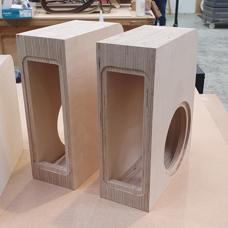 Two Bespoke speaker cabinets made from CNC cut layers of birch plywood sitting on a workshop bench