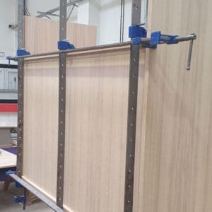 A partially built Oak veneer faced MDF display cabinet in production with long sash clamps holding it together whilst being glued