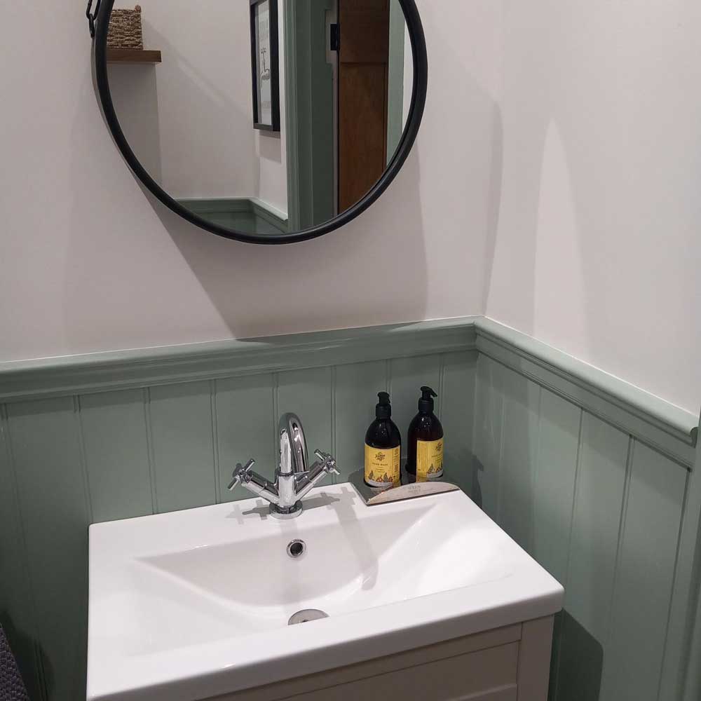 wall panelling dado rail painted in green in a bathroom behind a sink with tongue and groove panels