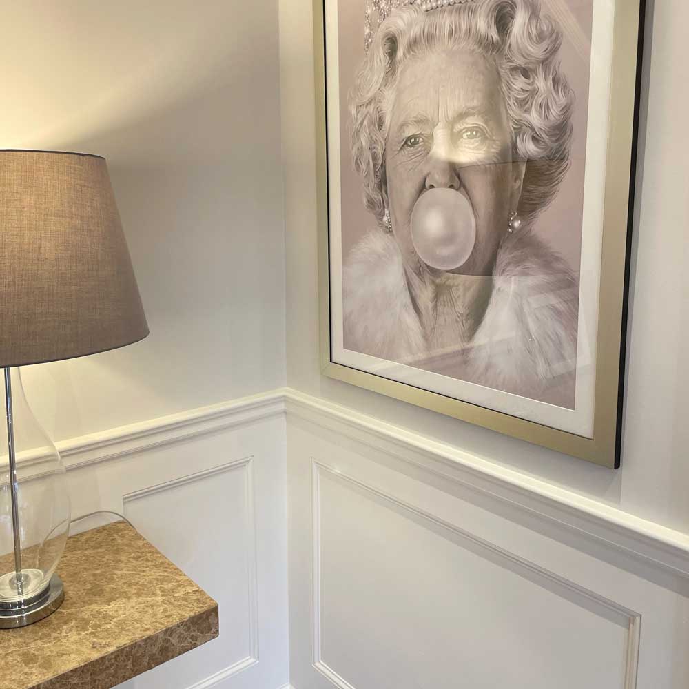 white wall panelling dado rail on top of traditional shaker wall panelling withe a picture of the queen above
