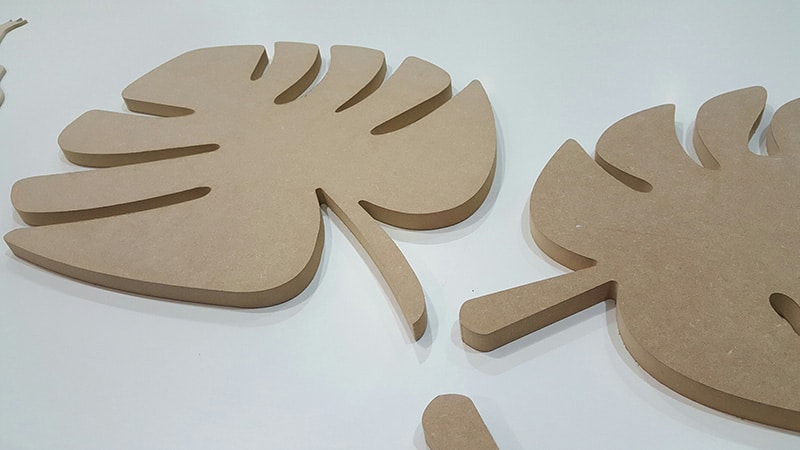 Palm leaf MDF shapes laying on a white panel