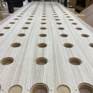 A CNC perforated Oak Veneer faced MDF panel on a workbench