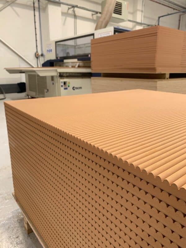 A large stack on Fire Rated Mini Ribbed panels in front of a CNC Machine