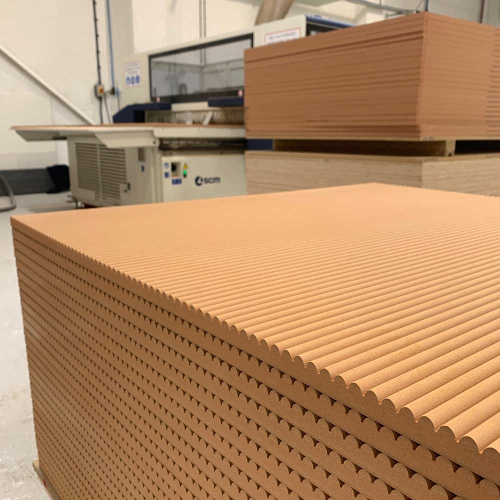 stack of fire rated mini ribbed panels in front of a cnc machine